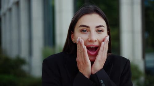 Surprised Woman with Hands on Face in Urban Setting