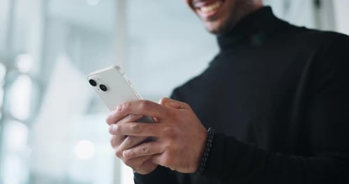 Smiling Man Using a Smartphone in Bright Office