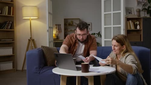 Couple reviewing bills at home with laptop computer
