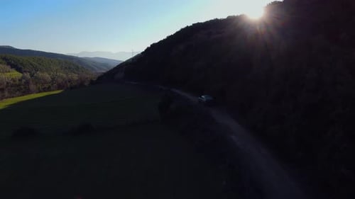 Areal shot of rally car driving fast off road during sunset