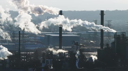 Industrielandschaft mit Schornsteinen, die Dampf vor klarem Himmel abgeben, Fernblick