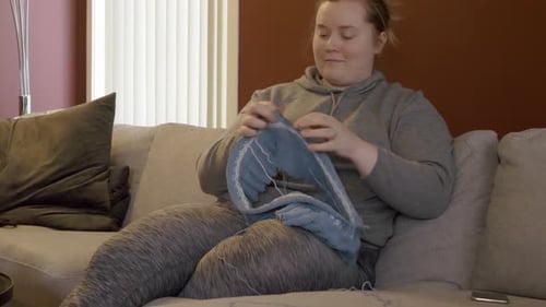 Woman Knitting a Blue Scarf on Couch