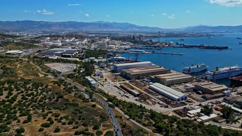 A bustling industrial port by the coastline with ships and factories, aerial view