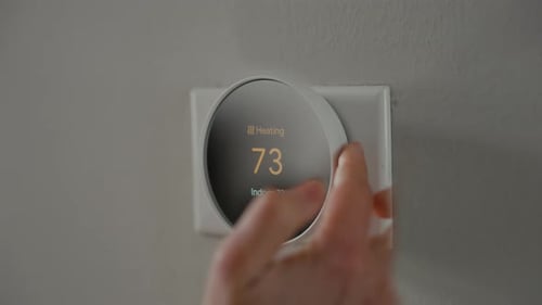 Adjusting a Smart Thermostat on Interior Wall