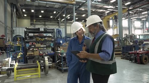 Transit workers meeting with digital tablet in maintenance facility slow motion