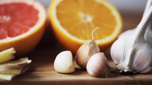 Ginger root grapefruit orange and garlic still life on wooden cutting board