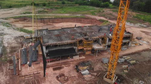 Aerial view capturing the movement of a crane, transporting construction materials behind.