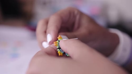 Child Hands Crafting a Colorful Beaded Star