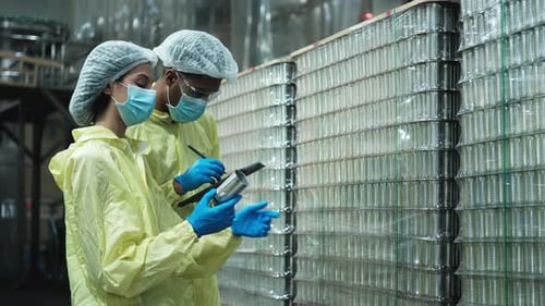 Deux superviseurs inspectent la qualité des contenants utilisés dans la fabrication d'aliments en conserve.