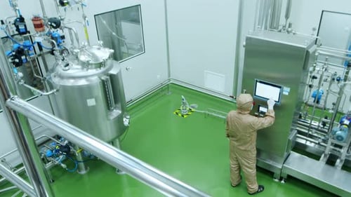 Technician or scientist in uniform work in high-tech stainless steel industrial processing tank