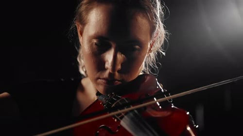 Woman Plays Red Violin in Dark Studio Close-Up