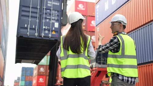 Caucasian business man and woman worker working in container terminal.