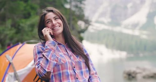 Smiling Woman Talking on Phone in Mountain Lake Setting
