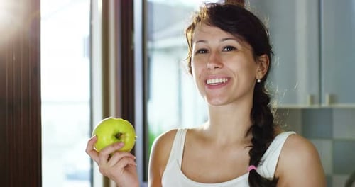 a summer afternoon a young girl eating a fresh green apple to keep fit respecting his diet and smi