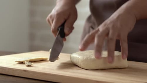 Person Slicing a Block of Tofu with Knife