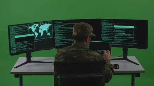 Back View Of Man Soldier Working With Tablet While Write Code With Multiple Screens In Green Screen