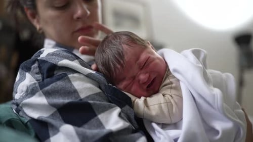 Woman Comforts Crying Infant Indoors, Close Up