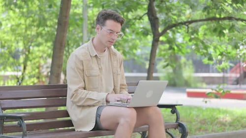 Young Adult Working on Laptop in Park