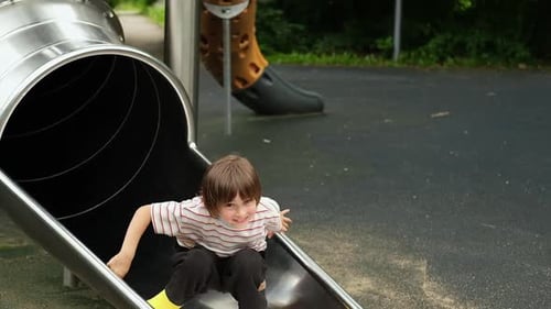 Metal Tube Slide on the Playground Boy is Going Down and Having Joy and Fun