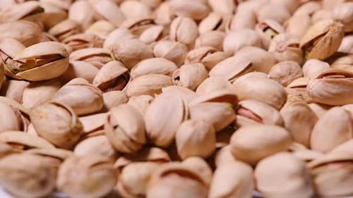 Pile of Delicious Pistachios Rotating Slowly on White