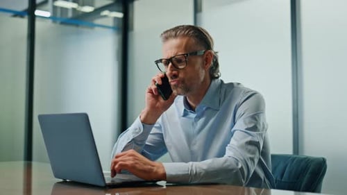 Man working at desk with laptop and phone
