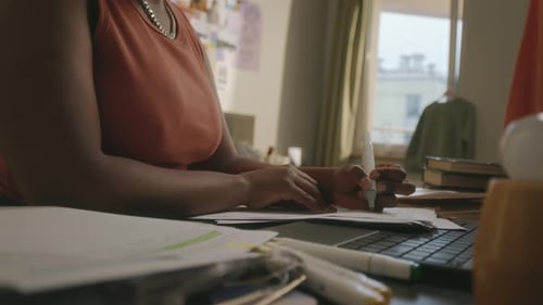 Adult Working At Desk On Computer And Papers
