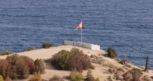 Spanish Flag Waving on Hill Near the Ocean