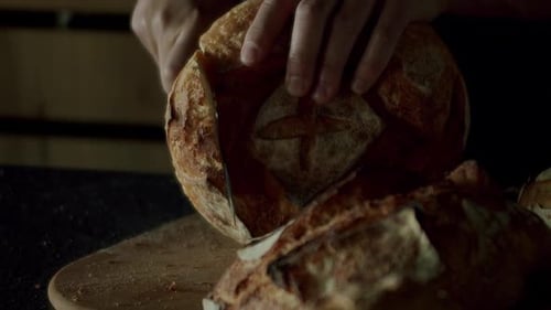 Cropped View of Man Baker Cutting Fresh Loaf Bread with Crispy Crust Using Knife