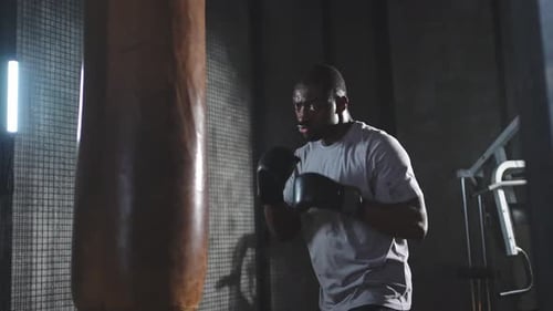 Fitness Workout in Gym Strong African Man Fighter Training Punches with Boxing Bag Healthy Boxer Man