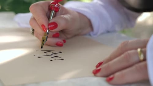 closeup of woman writing calligraphic letters with fountain pen, handheld