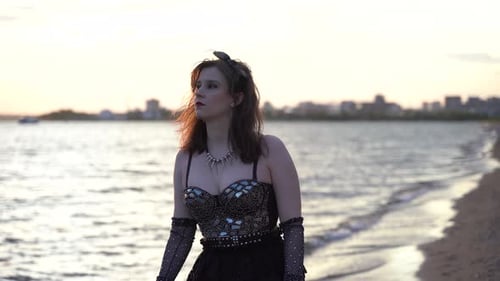 Young woman walking on the beach in black gothic clothes 4K