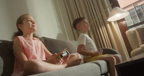 Linda niña y niño sonríen Los niños están jugando videojuegos en la televisión y juegan activamente juegos de ordenador