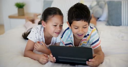 Children Smile Using Tablet Device on Bed at Home