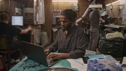 Diverse Employees Working with Laptop and Machinery in Garage