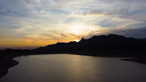 Aerial shot of a golden hour reflection on the surface of a natural lake. Colorful sunset.
