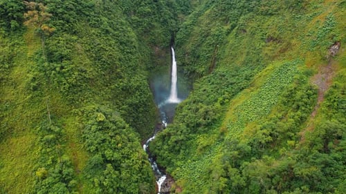 Aerial view of a tall waterfall cascading into a lush green valley in Costa Rica