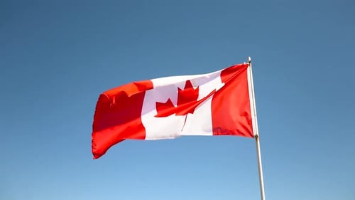 Canadian Flag Waving Against Blue Sky