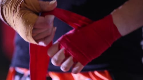 Extreme close-up view of professional female boxer wrapping hands with yellow and red protective ban
