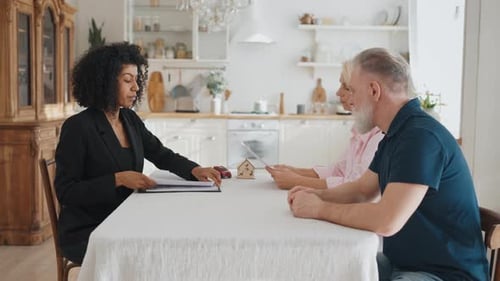 Meeting of Real Estate Broker and Senior Spouses in Home Kitchen Negotiation African American Woman