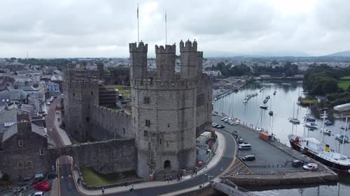 Ancient Caernarfon castle Welsh harbour town aerial view medieval waterfront landmark closeup orbit