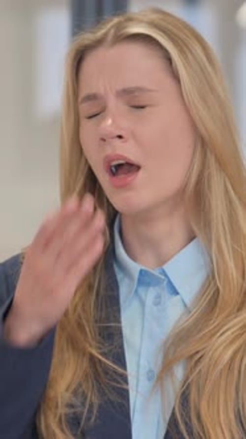 Tired Blonde Woman Yawning in the Workplace