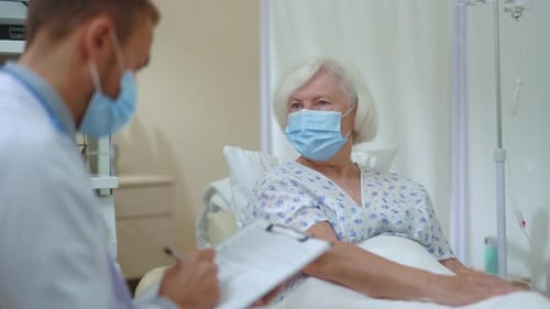 Caucasian Doctor Visiting Mature Caucasian Woman in Hospital Room Giving Professional Consultation