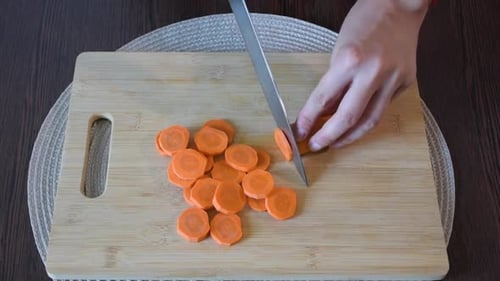 Woman's hand cutting a carrot.Top view.