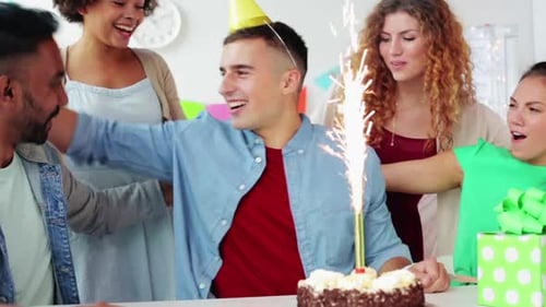 Friends celebrate a birthday with cake and sparkler