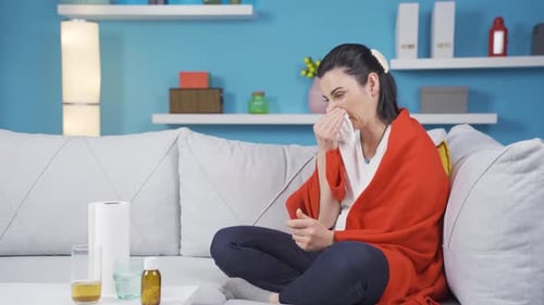 Woman Blowing Nose With Tissues on Couch