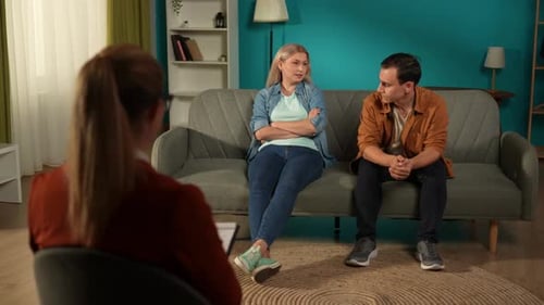 Wife and Husband Sit on the Couch in a Marriage Therapy Session with a Psychologist in the Office A