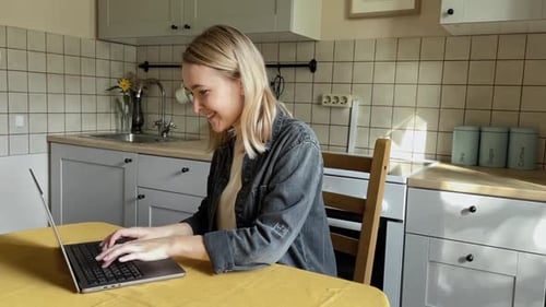 Woman Working on Laptop at Kitchen Table