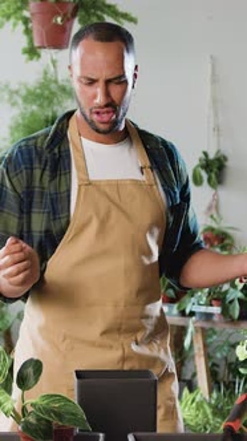 Attractive African American Man Working As Florist at Flower Shop Adding Fertilizers to Soil for