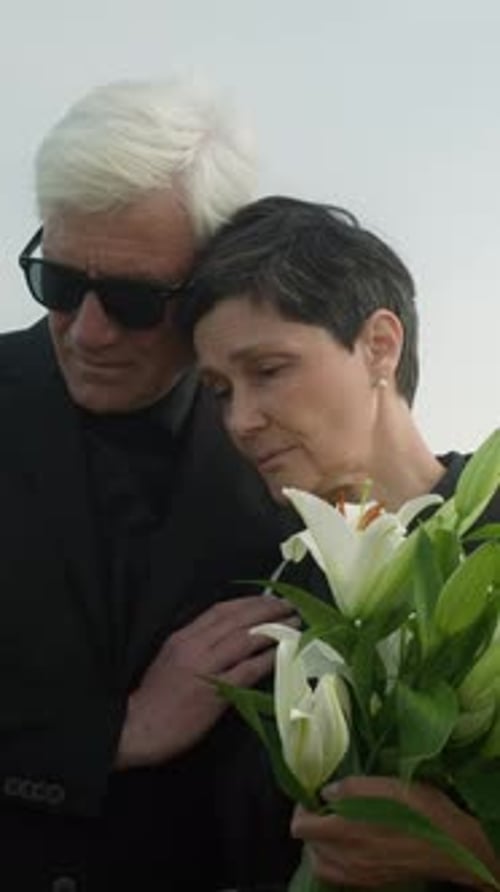 Woman Comforted by Man Holding Lilies