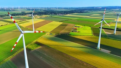 Wind turbines producing green energy. Aerial perspective on the windmills rotating in the fields.